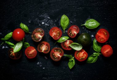 Kırmızı ve siyah yarım domates fesleğen yeşil yaprakları ile