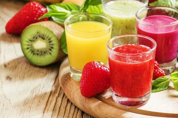 Colorful summer fruit and berry juices and smoothies in glasses