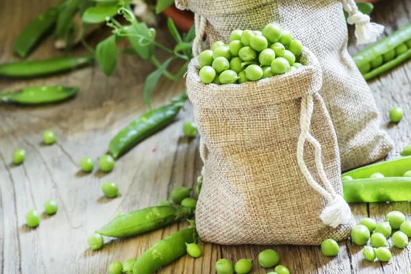 Geschälte grüne Erbsen in Leinensäcken — Stockfoto