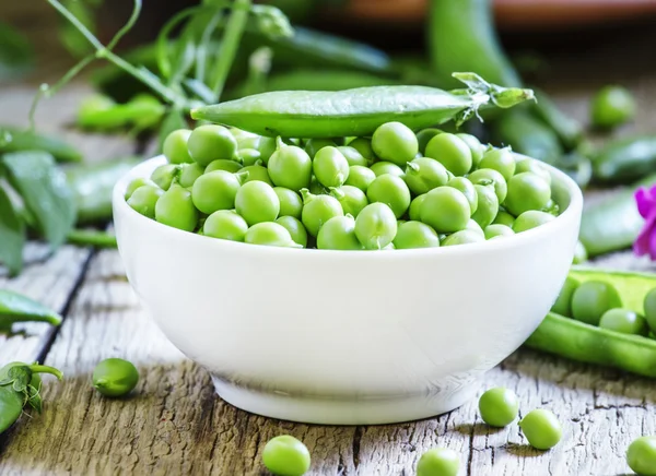 Peeled green peas in a white porcelain bowl — Stock Photo, Image