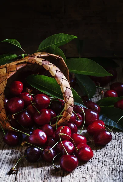 Dolci ciliegie mature con foglie in un cesto di vimini — Foto Stock