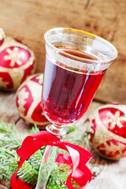 Kırmızı köpüklü şarap cam, ağaç dalları ve Noel topları 