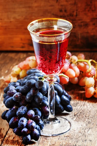Czerwone wino musujące w winogronach i szkła, niebieski, różowy — Zdjęcie stockowe
