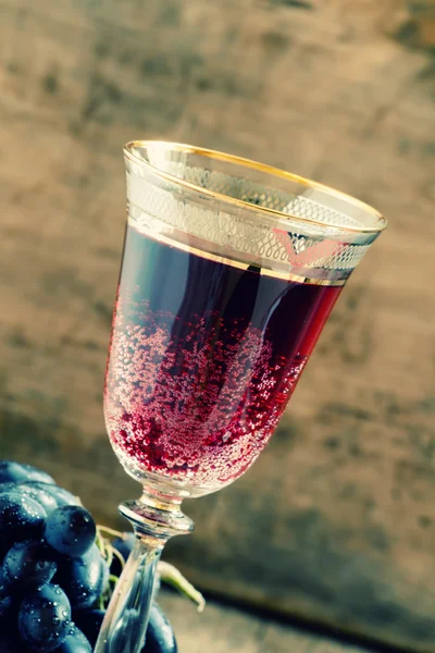Vino espumoso tinto en copa, uvas azules en bodega — Foto de Stock