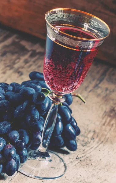 Red sparkling wine in the glass, blue grapes in the wine cellar — Stock Photo, Image