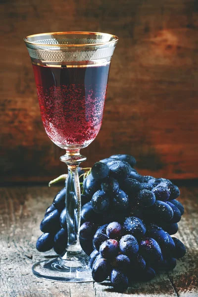 Czerwone wino musujące szkła, niebieski winogron w piwnicy z winami — Zdjęcie stockowe