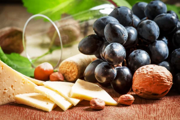 Queso, uvas azules, vid, frutos secos y un vaso — Foto de Stock