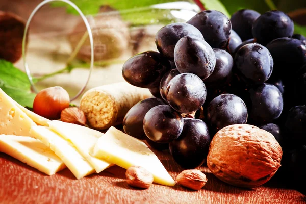 Queso, uvas azules, vid, frutos secos y un vaso — Foto de Stock