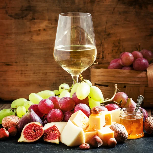 Vino blanco, queso, higos, frutos secos y uvas — Foto de Stock