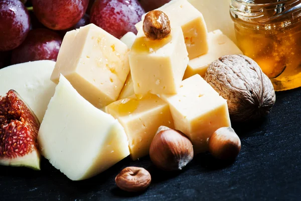 Käse, Feigen, Nüsse und Trauben auf dem alten Holzgrund — Stockfoto