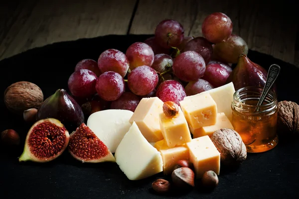 Käse, Feigen, Nüsse und Trauben auf dem alten Holzgrund — Stockfoto