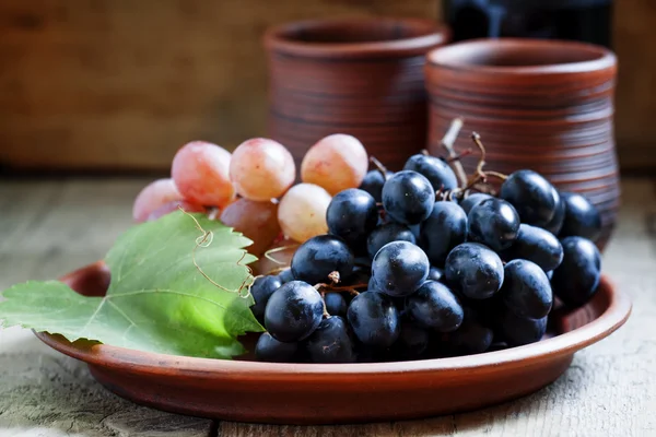 Uve blu e rosa su un piatto d'argilla — Foto Stock