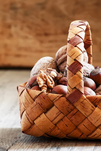 Hasselnötter och valnötter i en flätad korg — Stockfoto