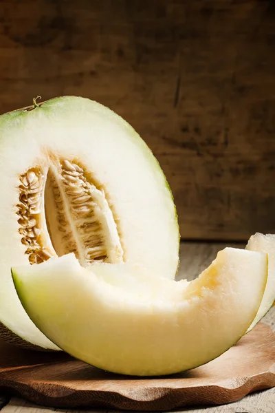 Cut melon and slices on a wooden table — Stock Photo, Image