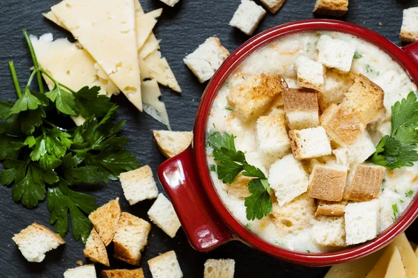 Soupe au fromage avec croûtons dans une casserole rouge — Photo