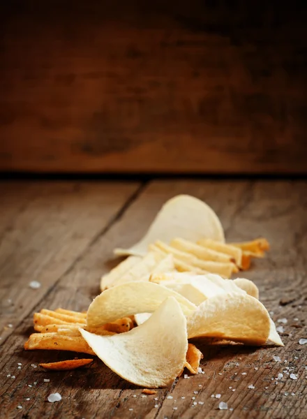 Chips and salt on old wooden table — Stock Photo, Image