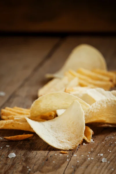 Chips and salt on old wooden table — Stock Photo, Image