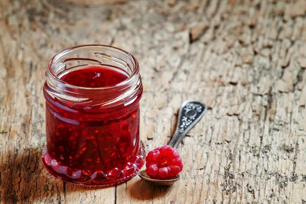 Mermelada de frambuesa en un frasco y frambuesa en una cuchara —  Fotos de Stock