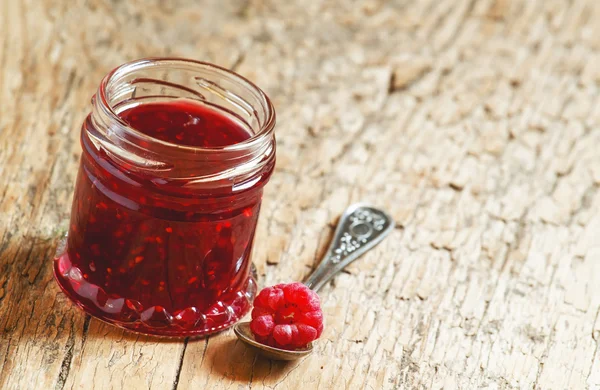 Confiture de framboises dans un bocal et framboise dans une cuillère — Photo