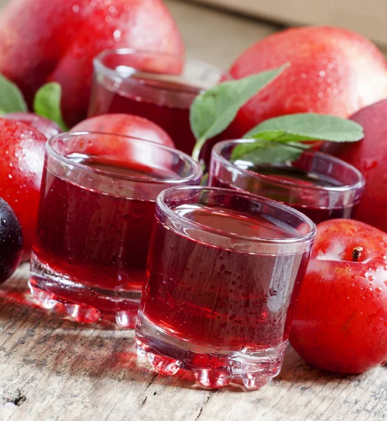 Ízletes friss gyümölcslé, vörös és kék édes szilva — Stock Fotó