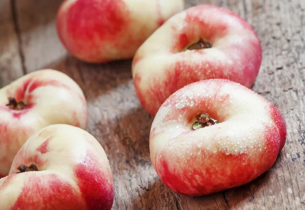 Flache rosa Nektarinen auf altem Holzgrund — Stockfoto