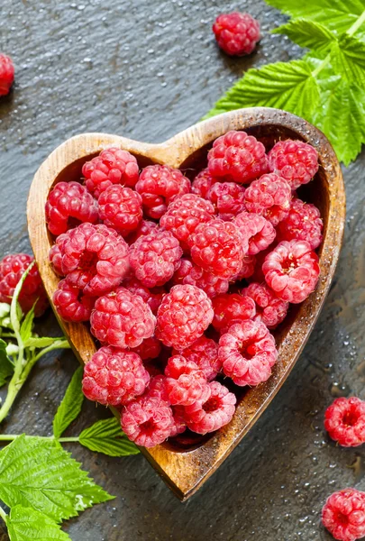 Fresh raspberries with leaves in a bowl in the shape of a heart — Stock Photo, Image