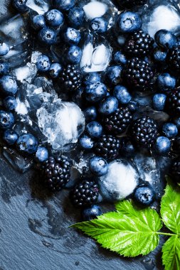 Buz karanlık bir arka plan üzerinde bir yaban mersini ve böğürtlen 