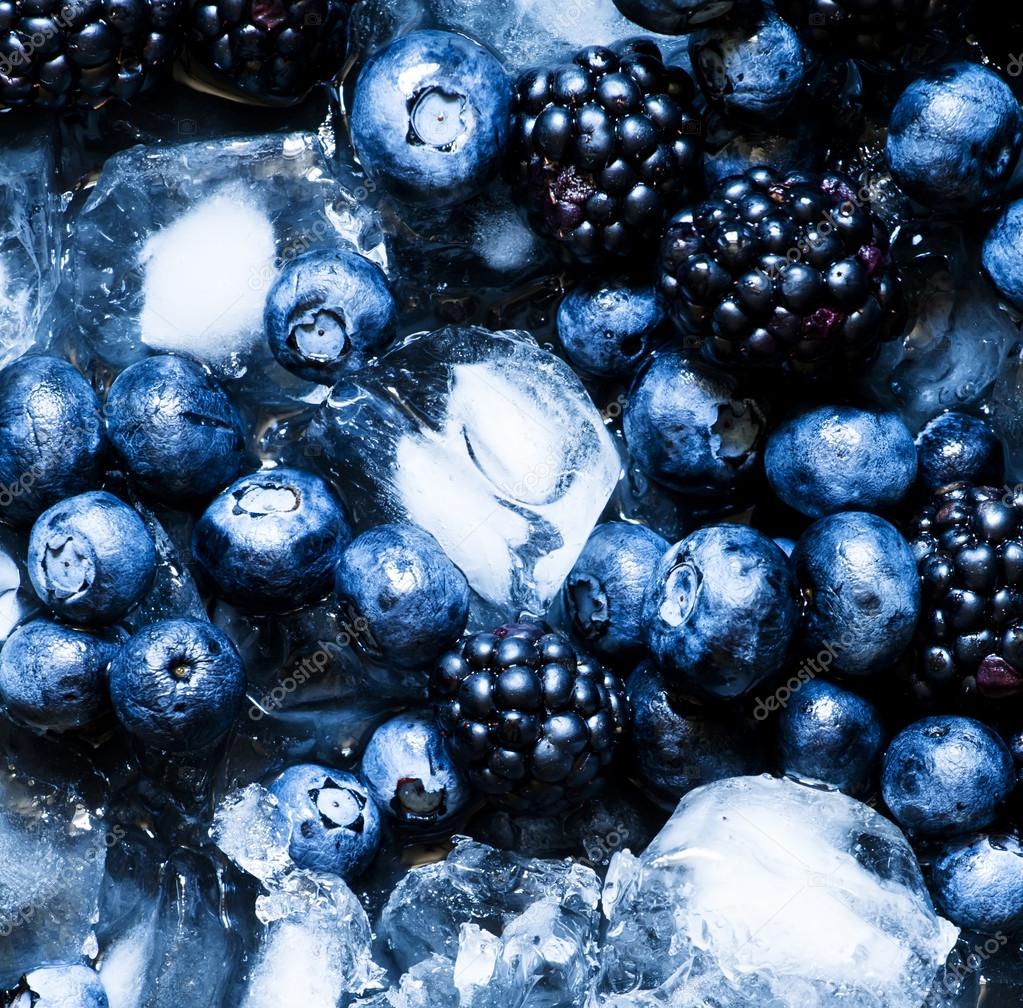 Blackberries and blueberries in ice on a dark background — Stock Photo