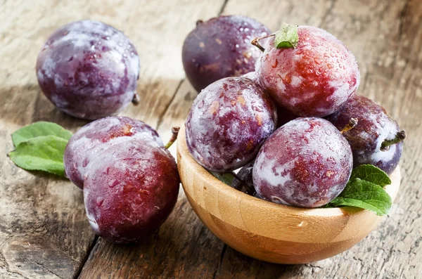 Ciruelas grandes moradas con gotas de agua y hojas —  Fotos de Stock