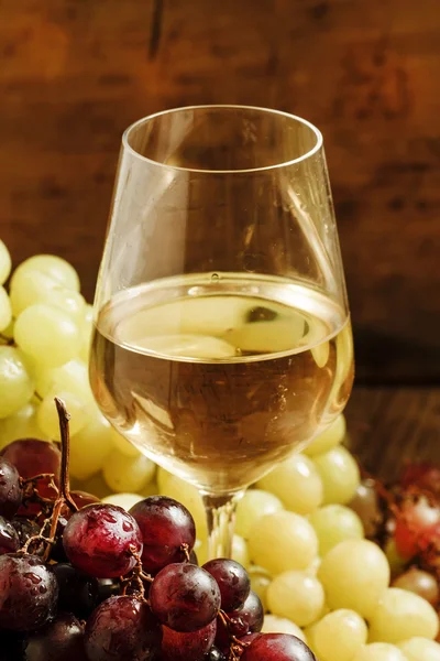 Vinho branco em um copo e uvas verdes e vermelhas — Fotografia de Stock