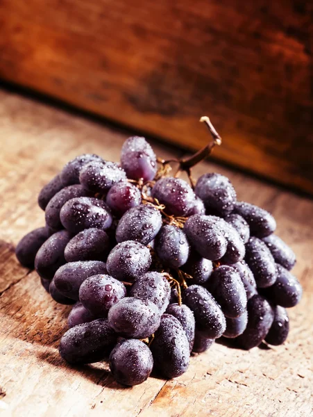 Uvas de vino púrpura en mesa de madera vieja — Foto de Stock