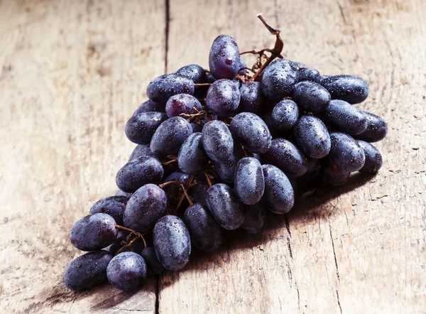 Uvas de vino púrpura en mesa de madera vieja — Foto de Stock