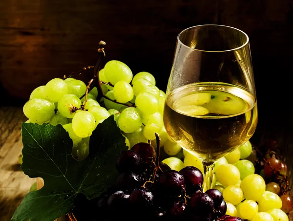 在玻璃和绿色和红色的葡萄在柳条篮子里的白葡萄酒 — 图库照片