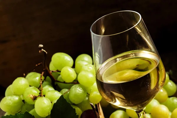 Weißwein im Glas und grüne und rote Trauben im Weidenkorb — Stockfoto