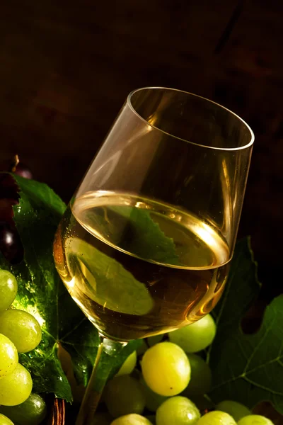 Vinho branco e uvas verdes numa cesta de vime numa adega — Fotografia de Stock