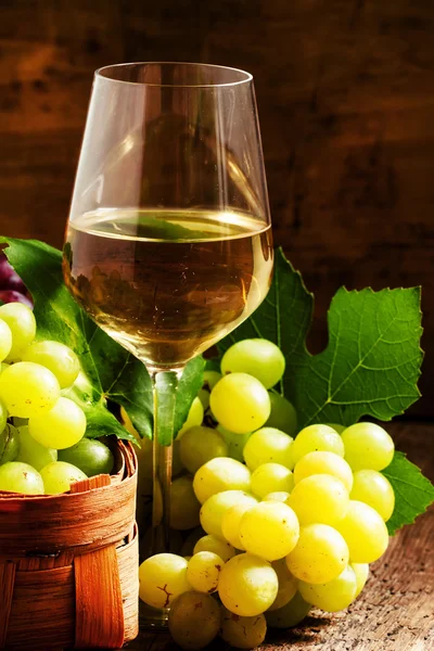 Белое вино и зеленый виноград в плетеной корзине в винном погребе — стоковое фото