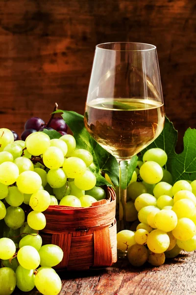 在酒窖的柳条篮子白红酒和绿色葡萄 — 图库照片