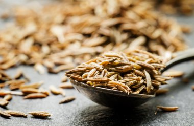 Zira ya da koyu arka plan üzerinde metal bir kaşık kimyon