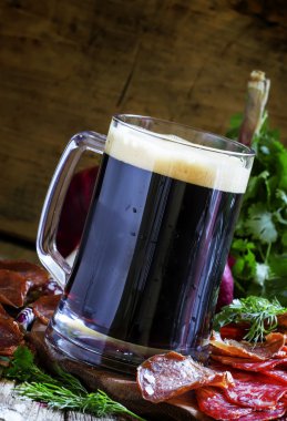 Büyük bardak koyu köpük bira, sosis ve et meze