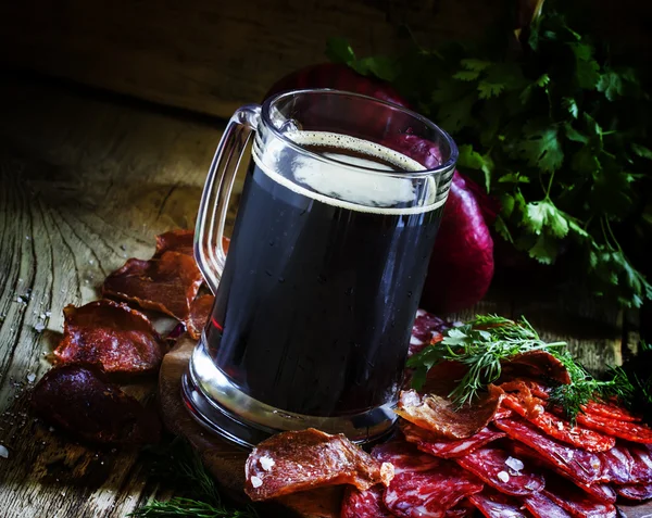 Большой стакан тёмного пены, сосисок и мясных закусок — стоковое фото
