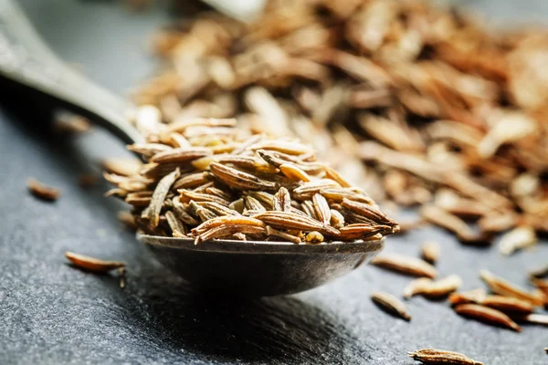 Zira or cumin in a metal spoon on a dark background — Stock Photo, Image