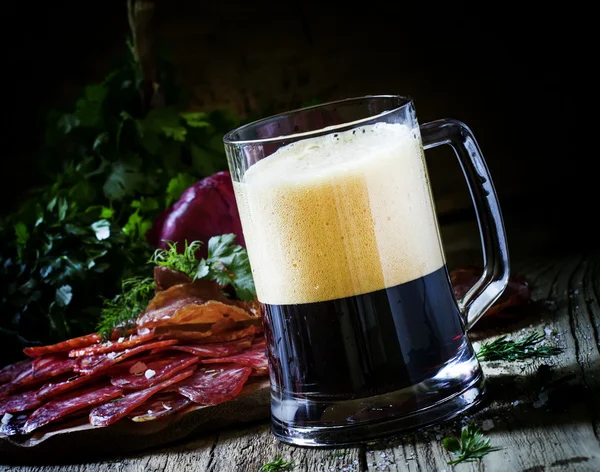 Grande copo de cerveja de espuma escura, salsicha e aperitivos de carne — Fotografia de Stock