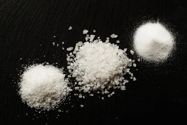 Drei Arten von Salz auf dunklem Steinhintergrund — Stockfoto