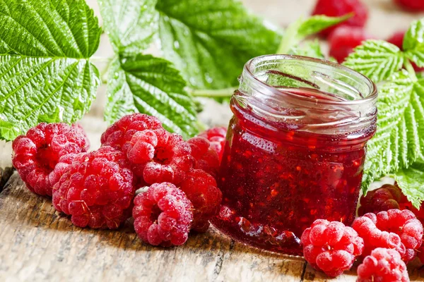 Raspberry jam with fresh raspberries and green leaves — Stock Photo, Image