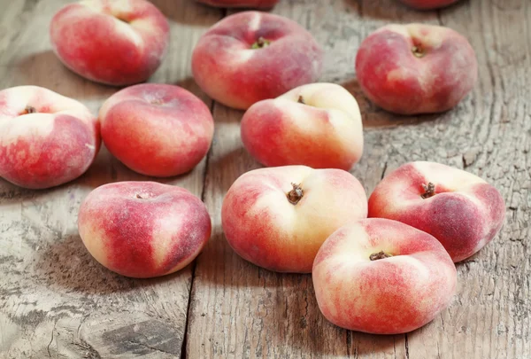 Platt rosa persikor på en gammal trä bakgrund — Stockfoto