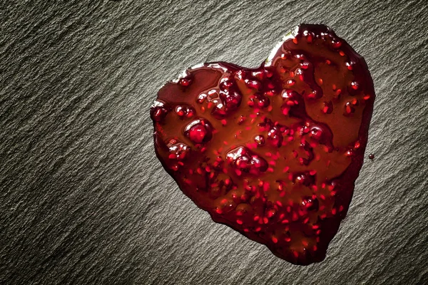 Drops of red raspberry jam in the form of heart — Stock Photo, Image