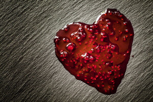 Drops of red raspberry jam in the form of heart