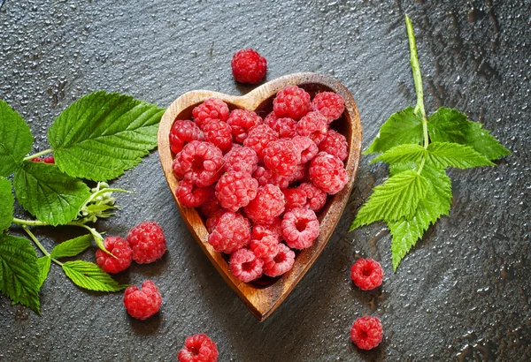 Frische Himbeeren mit Blättern in einer Schüssel in Herzform — Stockfoto