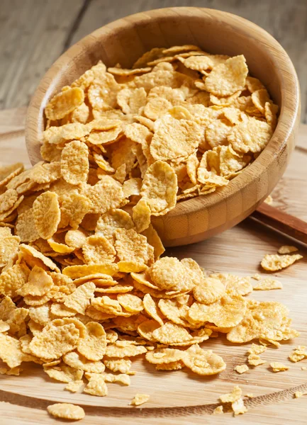 Corn flakes poured out of a wooden bowl
