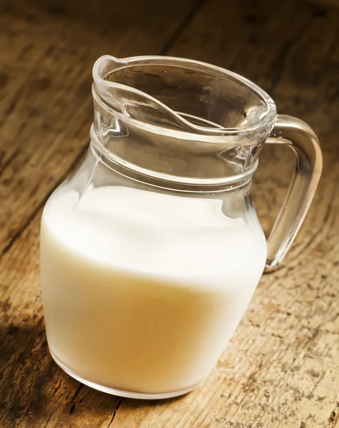 Kruik van melk op oude houten tafel — Stockfoto